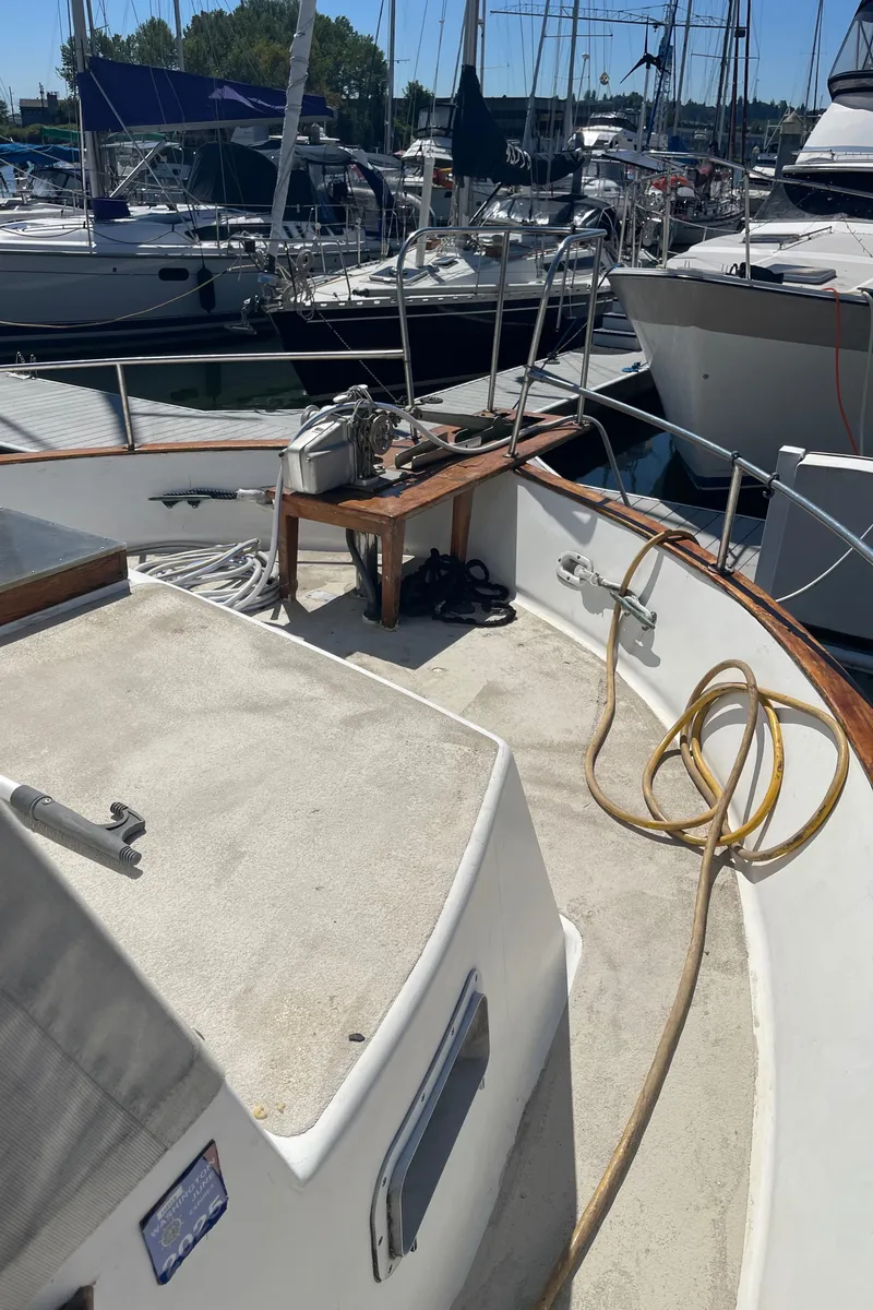 Slide: The Image of 1978 Californian Tri-Cabin Trawler deck with marina view, featuring ropes and equipment. - 15