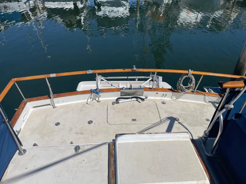 Slide: The Image of 1978 Californian Tri-Cabin Trawler deck with wooden railings and marina view. - 3