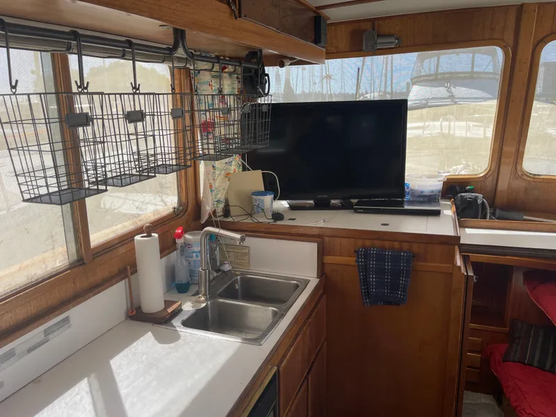 Slide: The Image of 1978 Californian Tri-Cabin Trawler interior with kitchen sink, TV, and storage baskets. - 39
