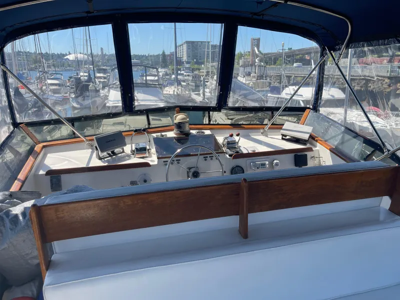 Slide: The Image of 1978 Californian Tri-Cabin Trawler helm with marina view, featuring navigation equipment and wooden accents. - 4