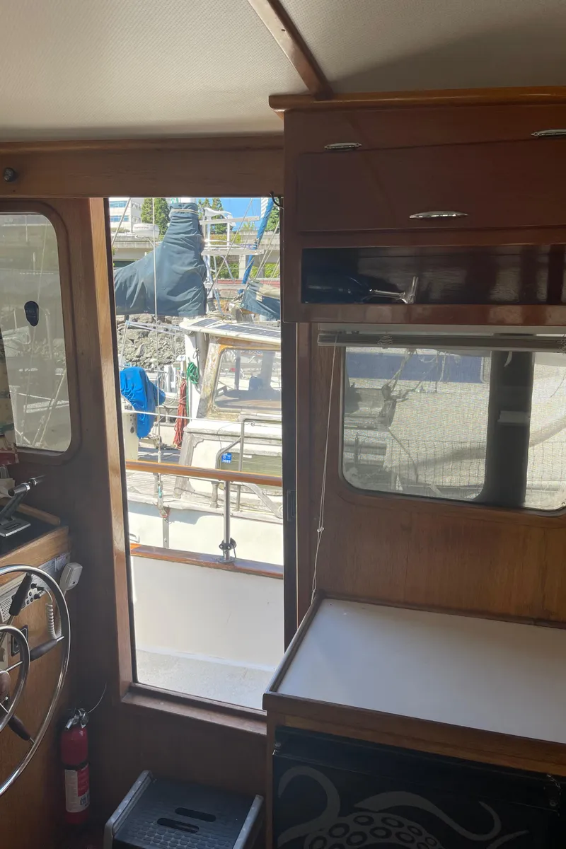 Slide: The Image of 1978 Californian Tri-Cabin Trawler interior with steering wheel and window view of marina. - 40