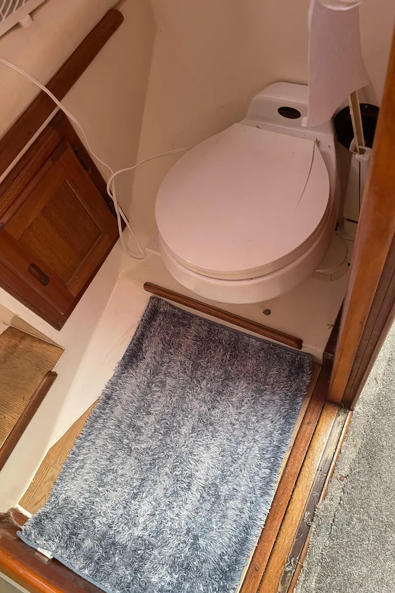 Slide: The Image of 1978 Californian Tri-Cabin Trawler bathroom with toilet, wooden cabinet, and gray rug. - 43