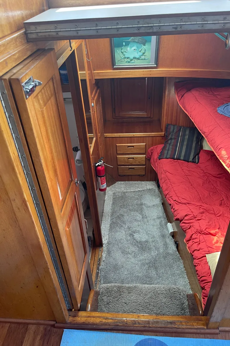 Slide: The Image of 1978 Californian Tri-Cabin Trawler interior with wooden cabinetry and red bedding. - 44