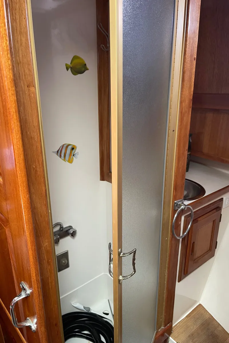 Slide: The Image of 1978 Californian Tri-Cabin Trawler shower with wooden doors and fish decorations. - 45