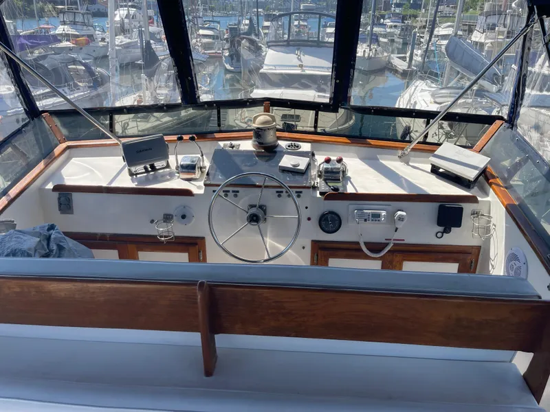 Slide: The Image of 1978 Californian Tri-Cabin Trawler helm with steering wheel, navigation equipment, and marina view. - 8