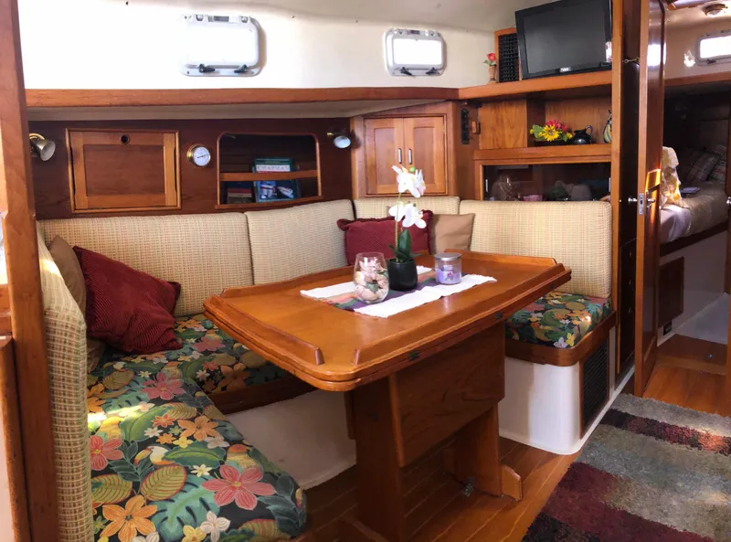 Slide: The Image of Cozy interior of a 1989 Nonsuch 33 sailboat with floral cushions and wooden table. - 2