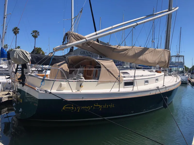 Slide: The Image of 1989 Nonsuch 33 sailboat docked in marina, clear blue sky, palm trees in background. - 20