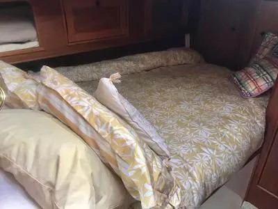 Slide: The Image of Cozy cabin bed in 1989 Nonsuch 33 sailboat with floral bedding and plaid pillows. - 4