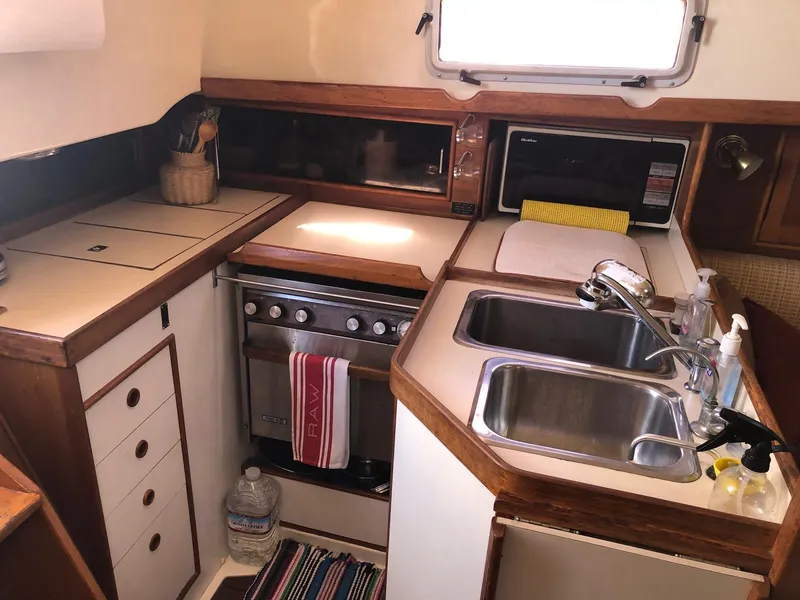 Slide: The Image of 1989 Nonsuch 33 yacht kitchen with stove, double sink, and storage cabinets. - 6