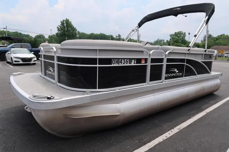 Slide: The Image of 2020 Bennington 20 SLV pontoon boat parked in a lot, featuring sleek design and canopy. - 8
