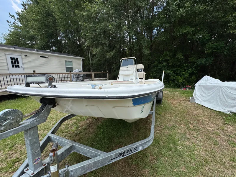 Slide: The Image of 2017 Mako Pro Skiff 19 CC on trailer, parked near a house and trees. - 15