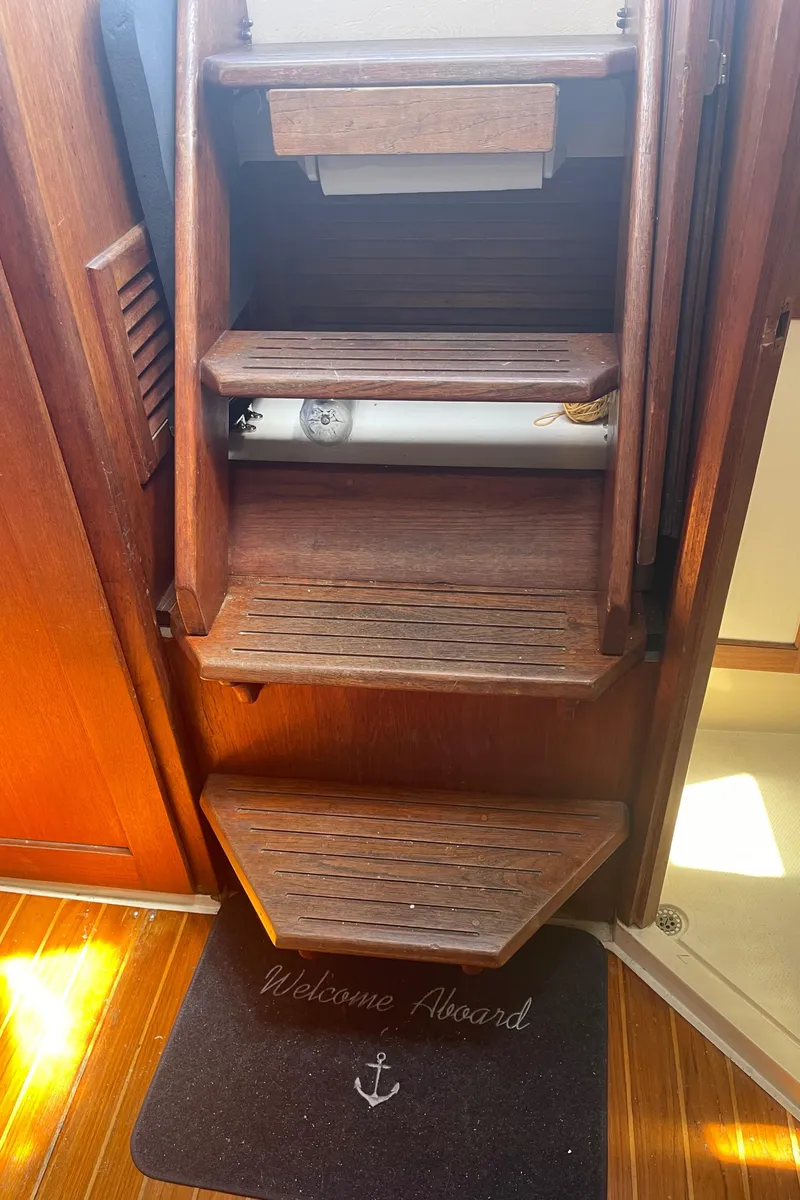 Slide: The Image of Wooden steps inside a 1986 Catalina 34 sailboat with a "Welcome Aboard" mat. - 44