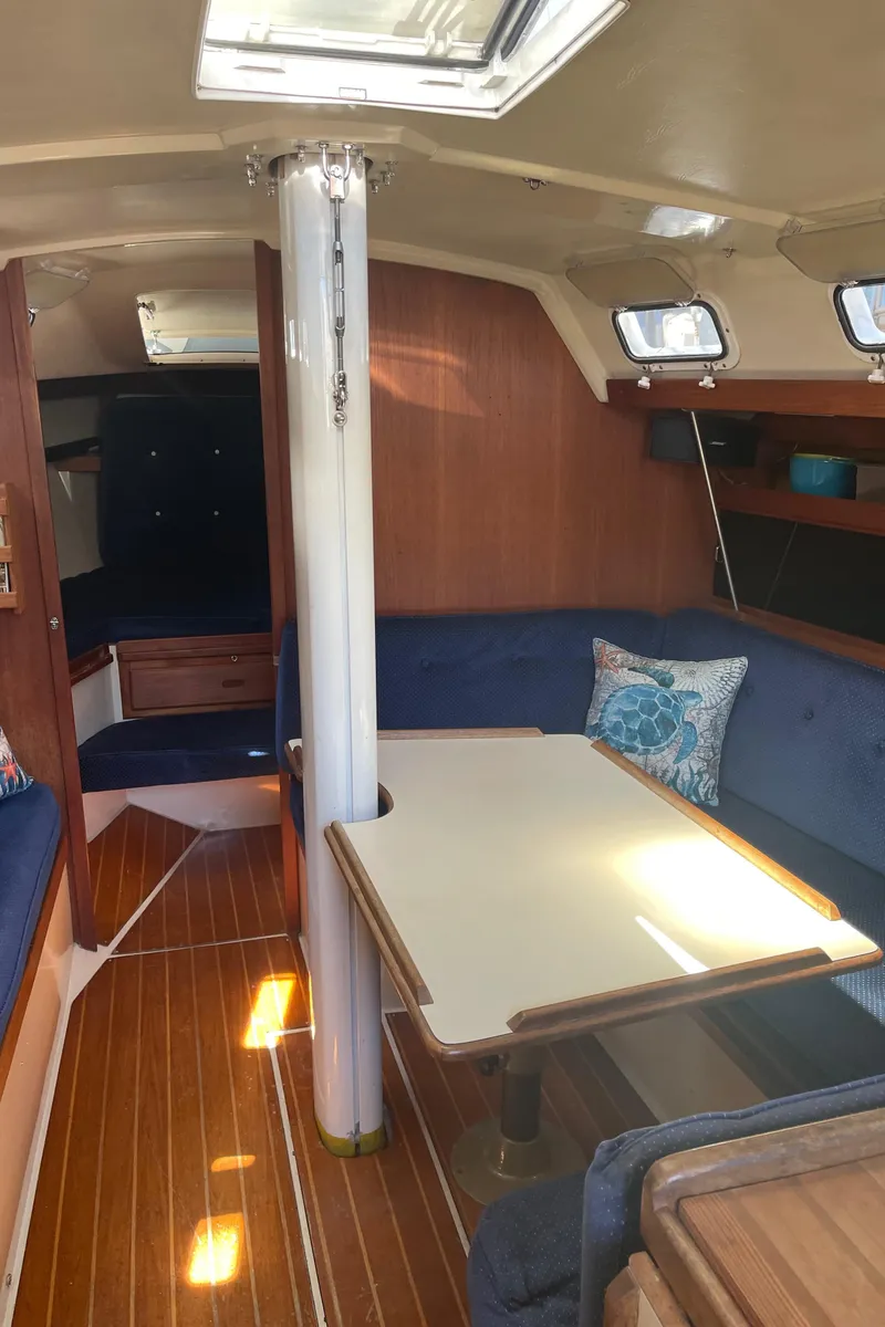 Slide: The Image of Interior of 1986 Catalina 34 sailboat with wooden flooring and cozy seating area. - 49