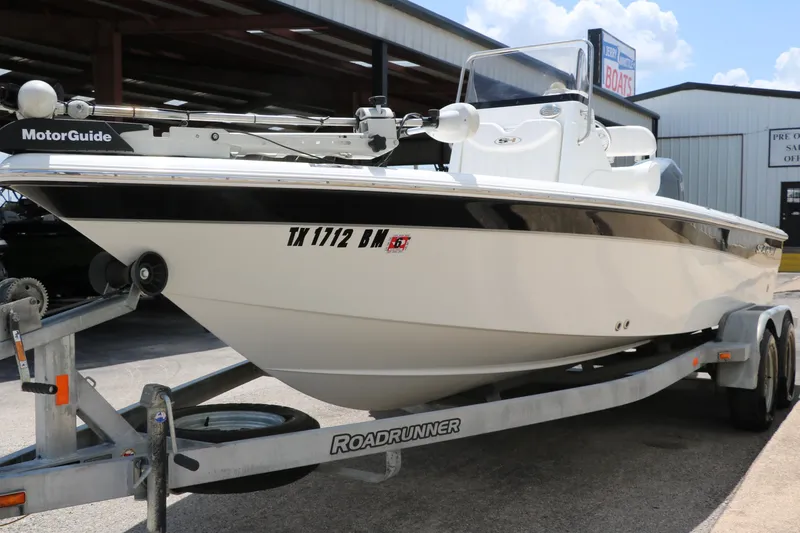 Slide: The Image of 2011 Sea Hunt XP-21 boat on trailer, displayed outdoors near a boat dealership. - 6
