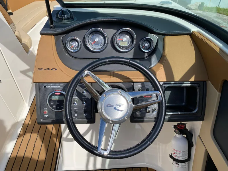 Slide: The Image of 2015 Sea Ray 240 Sundeck dashboard with steering wheel and gauges. - 16