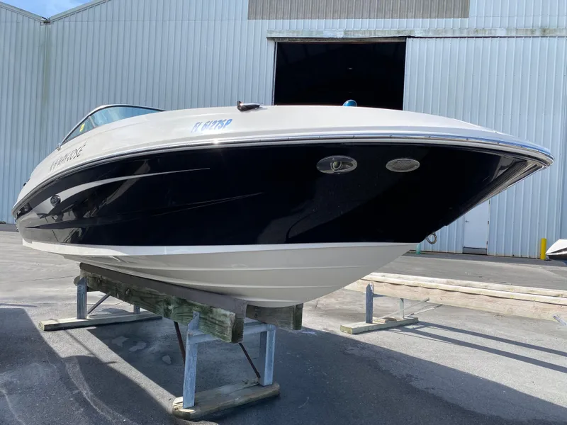 Slide: The Image of 2015 Sea Ray 240 Sundeck boat on a stand, outside a large warehouse. - 22