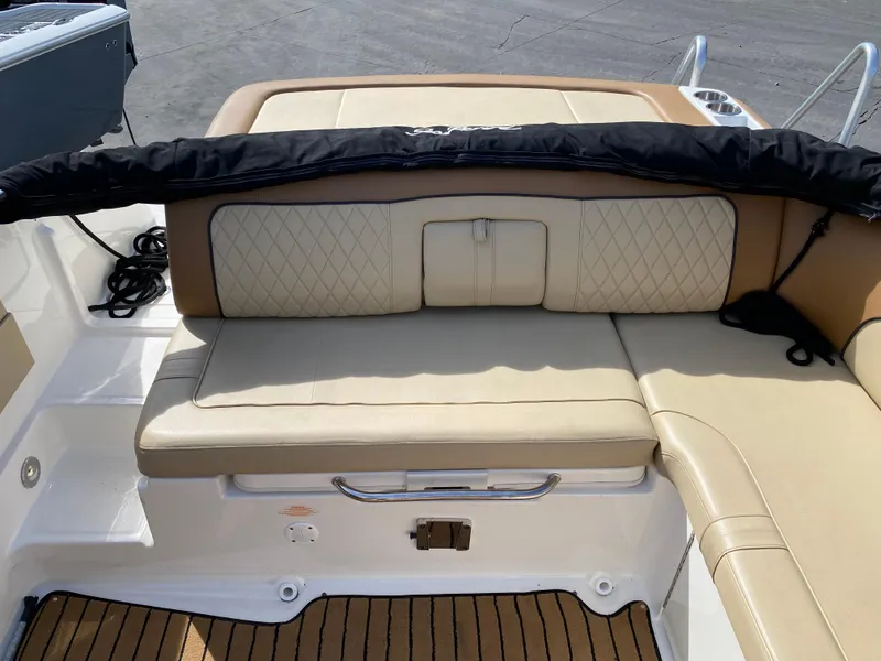Slide: The Image of 2015 Sea Ray 240 Sundeck boat interior with beige cushioned seating and storage. - 6