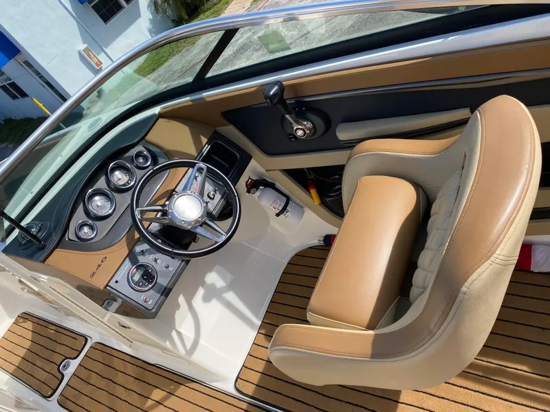 Slide: The Image of 2015 Sea Ray 240 Sundeck cockpit with tan seating and modern dashboard controls. - 7