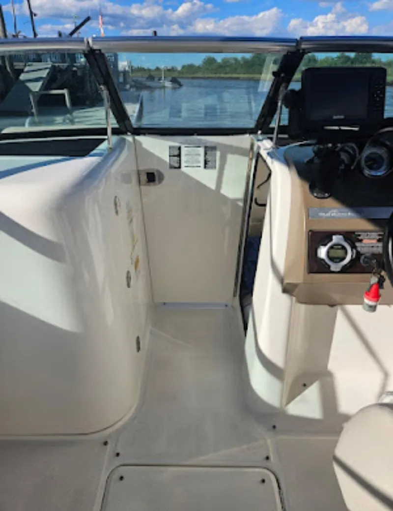 Slide: The Image of 2013 Sea Ray 260 Sundeck cockpit with steering console, overlooking calm waters and blue sky. - 10