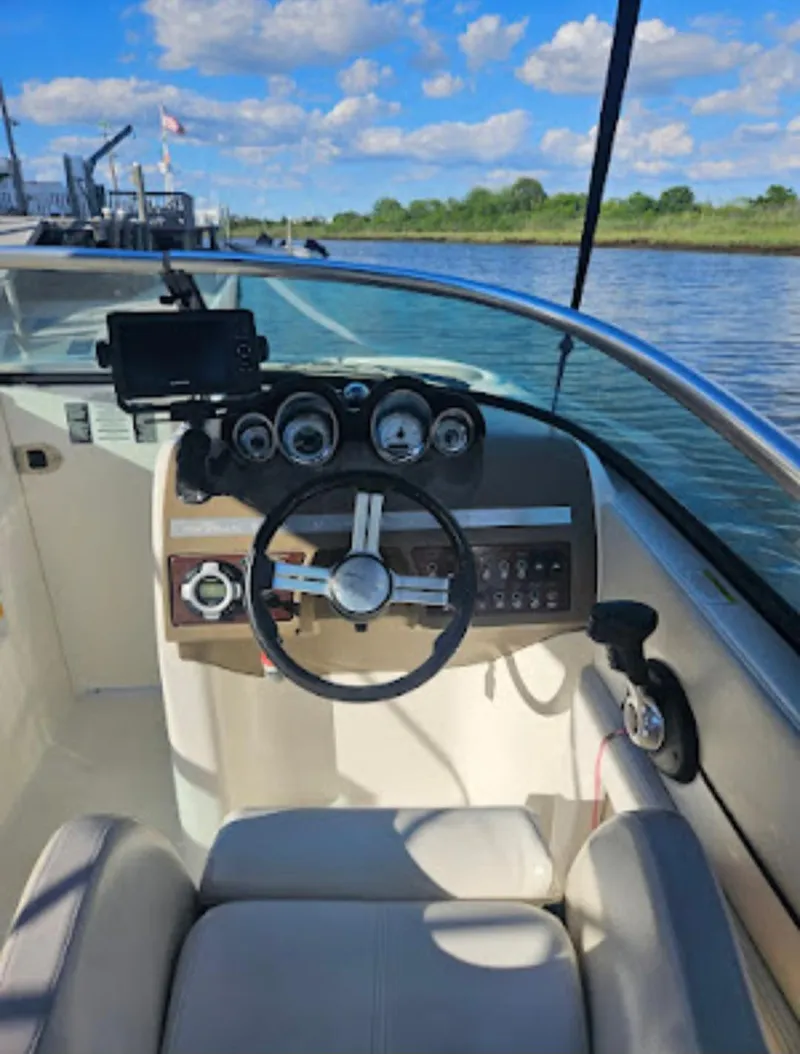 Slide: The Image of 2013 Sea Ray 260 Sundeck boat dashboard with steering wheel and gauges, docked by a scenic river. - 12