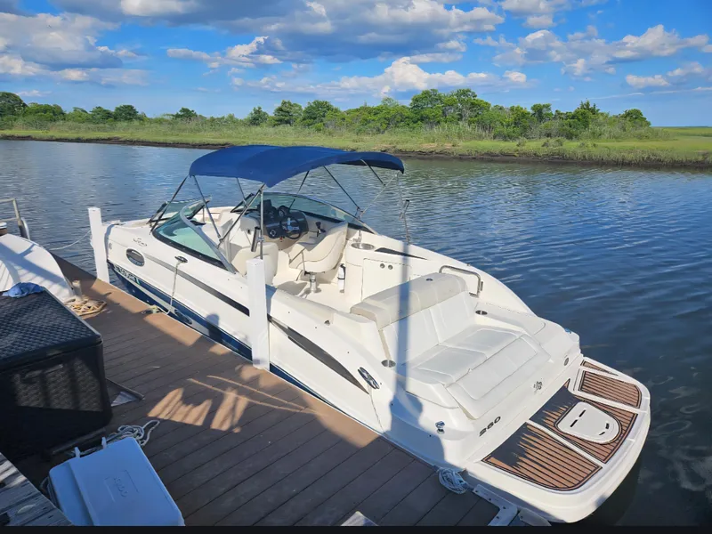 Slide: The Image of 2013 Sea Ray 260 Sundeck boat docked on a serene river under a blue sky. - 2