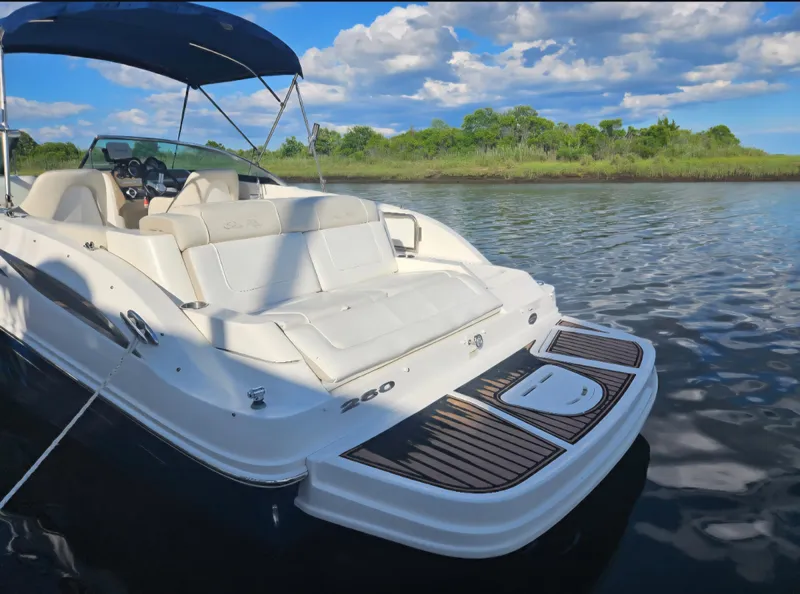 Slide: The Image of 2013 Sea Ray 260 Sundeck boat on calm water with lush green shoreline. - 22