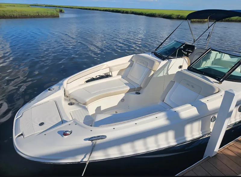 Slide: The Image of 2013 Sea Ray 260 Sundeck boat docked on calm water, featuring spacious seating and sleek design. - 23