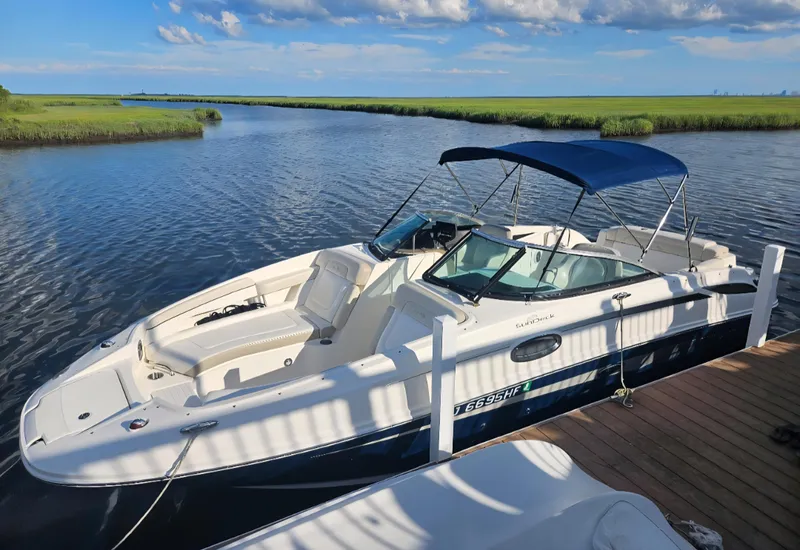 Slide: The Image of 2013 Sea Ray 260 Sundeck boat docked on a serene waterway under a blue sky. - 24