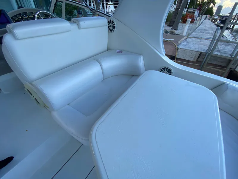 Slide: The Image of 2002 Cruisers Yachts 3372 Express interior with white seating and table, dockside view. - 13