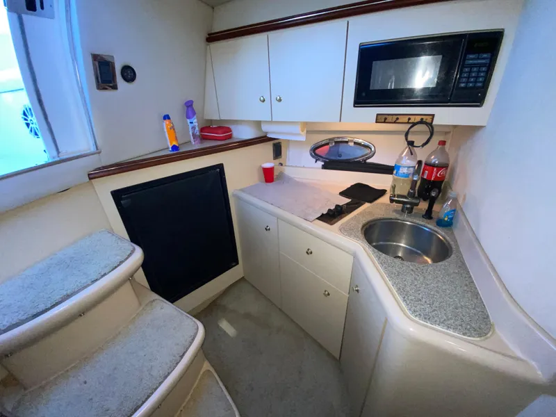Slide: The Image of 2002 Cruisers Yachts 3372 Express cabin kitchen with microwave, sink, and storage cabinets. - 17