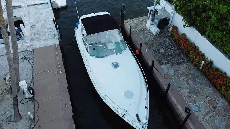 Slide: The Image of 2002 Cruisers Yachts 3372 Express docked beside a stone walkway and lush greenery. - 6