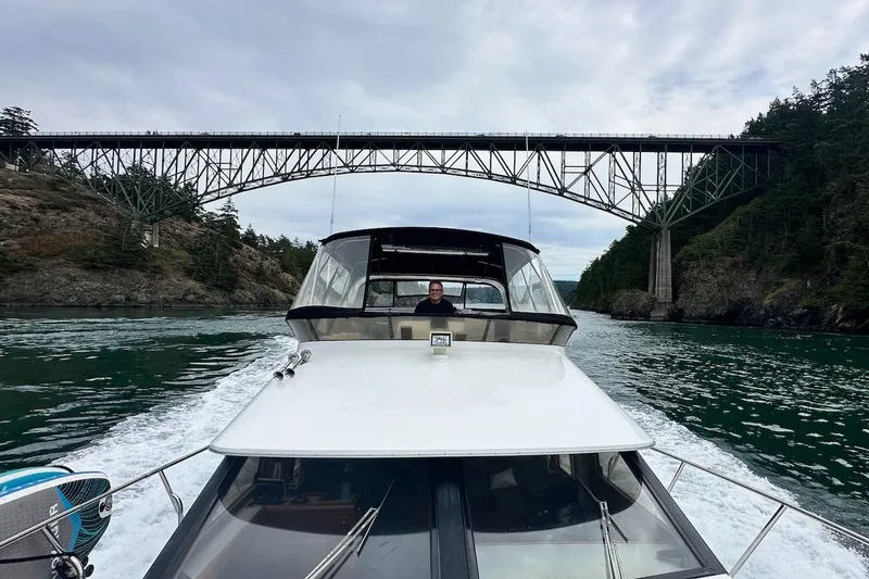 Slide: The Image of Ocean Alexander 460 yacht cruising under a scenic bridge, surrounded by lush greenery, 1993 model. - 5