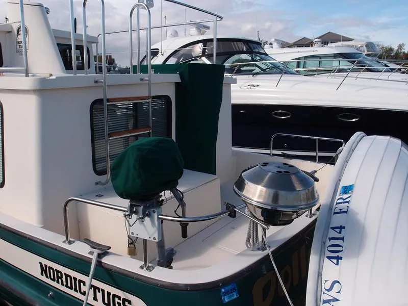 Slide: The Image of 1998 Nordic Tug 32 docked, featuring green canopy and adjacent luxury yacht. - 5