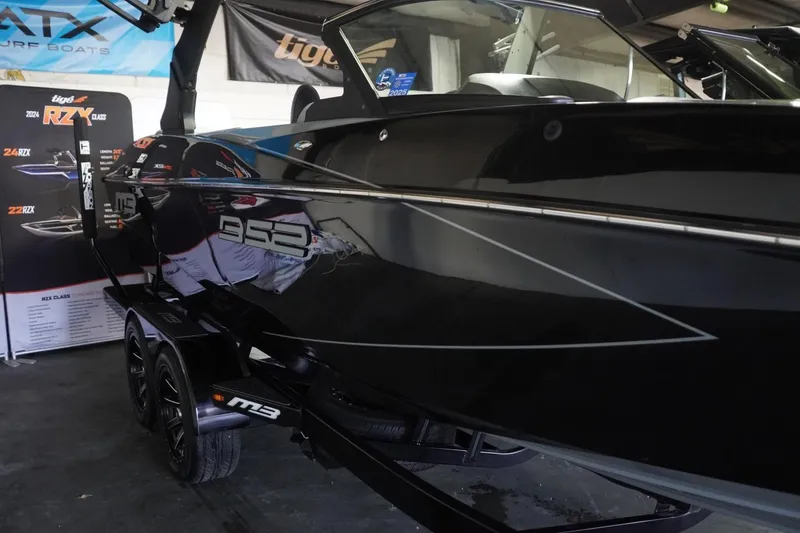 Slide: The Image of 2024 MB B52 23 Classic boat in showroom, sleek black design, on trailer. - 15