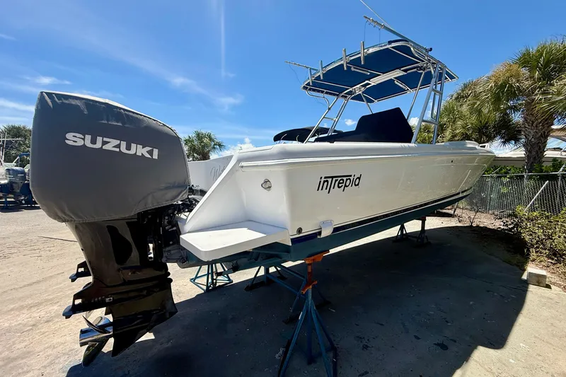 Slide: The Image of 2002 Intrepid 323 Cuddy boat with Suzuki outboard motor on stands, sunny day. - 10