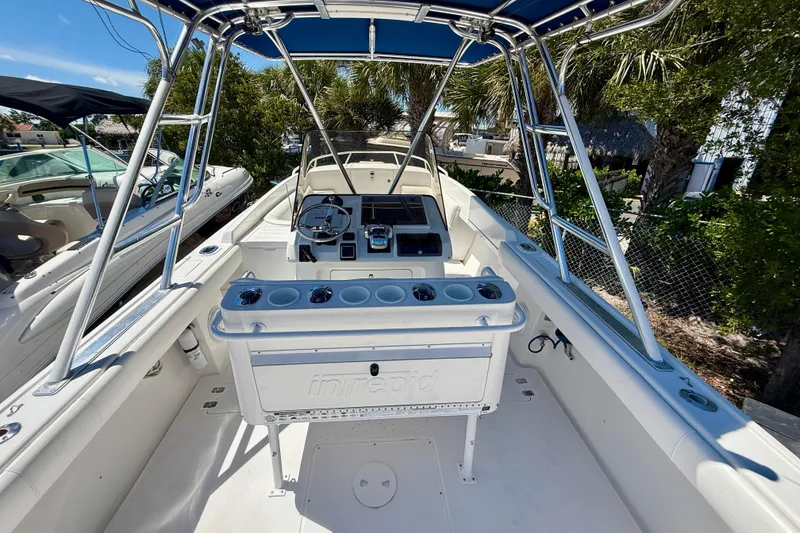 Slide: The Image of 2002 Intrepid 323 Cuddy boat interior with steering console and seating under blue canopy. - 18