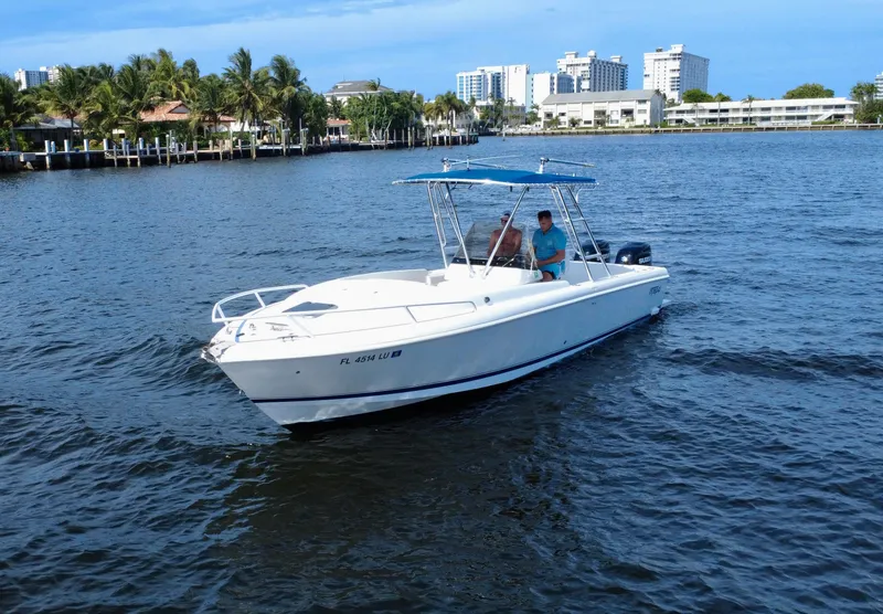 Slide: The Image of 2002 Intrepid 323 Cuddy boat cruising on a sunny day near waterfront buildings. - 2