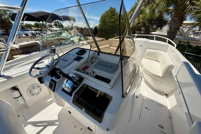 Slide: The Image of 2002 Intrepid 323 Cuddy boat cockpit with steering wheel, Garmin navigation, and seating under clear skies. - 23