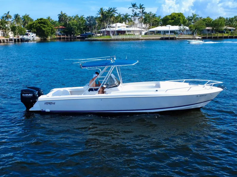 Slide: The Image of 2002 Intrepid 323 Cuddy boat on water, featuring Suzuki outboard motor, with scenic waterfront backdrop. - 5