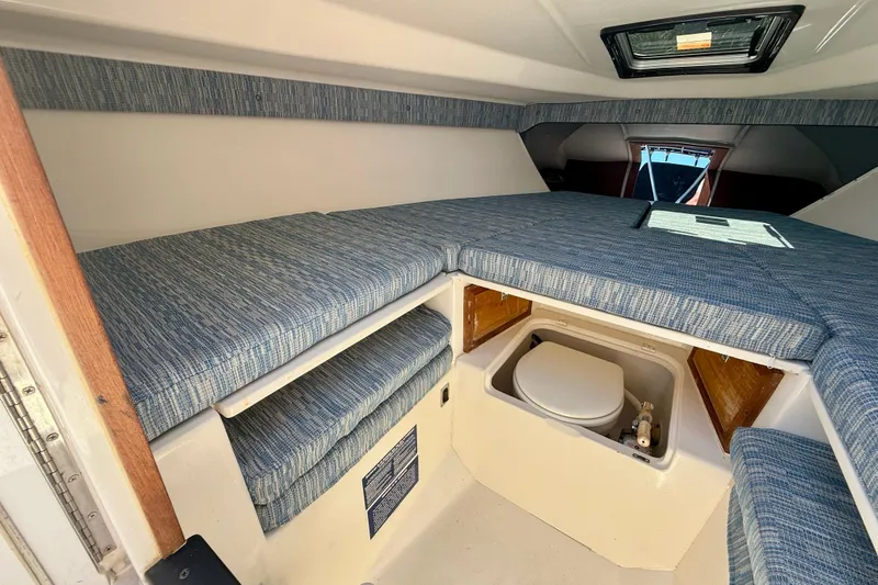 Slide: The Image of Interior of 2002 Intrepid 323 Cuddy boat with blue cushioned seating and compact toilet. - 51
