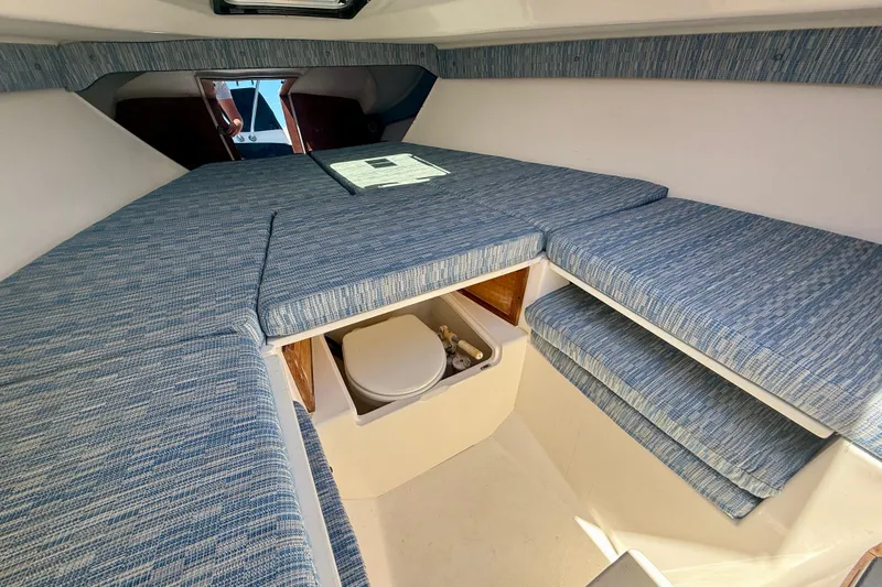Slide: The Image of Interior of 2002 Intrepid 323 Cuddy with blue cushioned seating and compact toilet. - 52