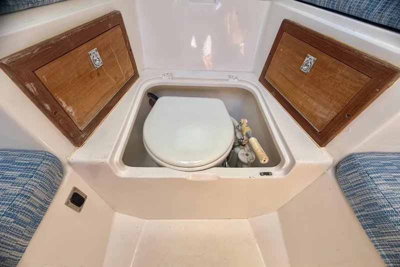 Slide: The Image of 2002 Intrepid 323 Cuddy boat interior with built-in toilet and wooden storage compartments. - 53