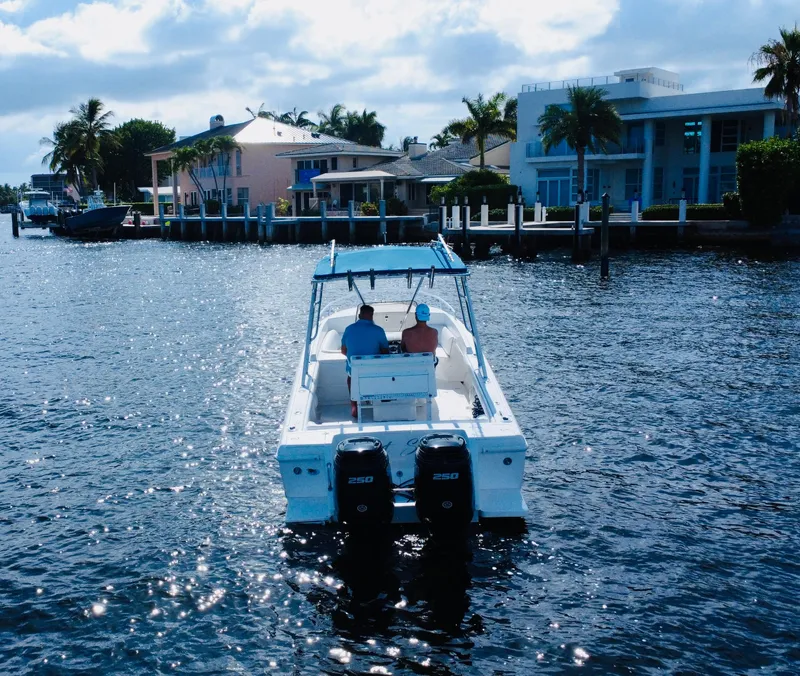 Slide: The Image of 2002 Intrepid 323 Cuddy boat cruising near waterfront homes under a partly cloudy sky. - 6