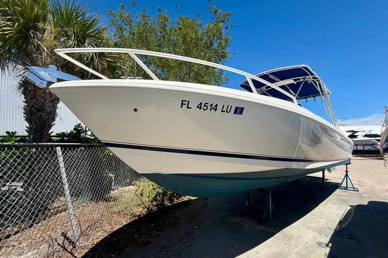Slide: The Image of 2002 Intrepid 323 Cuddy boat on stands, sunny day, palm trees in background. - 7