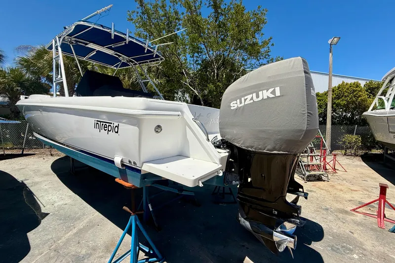 Slide: The Image of 2002 Intrepid 323 Cuddy boat with Suzuki outboard motor, parked outdoors on a sunny day. - 9