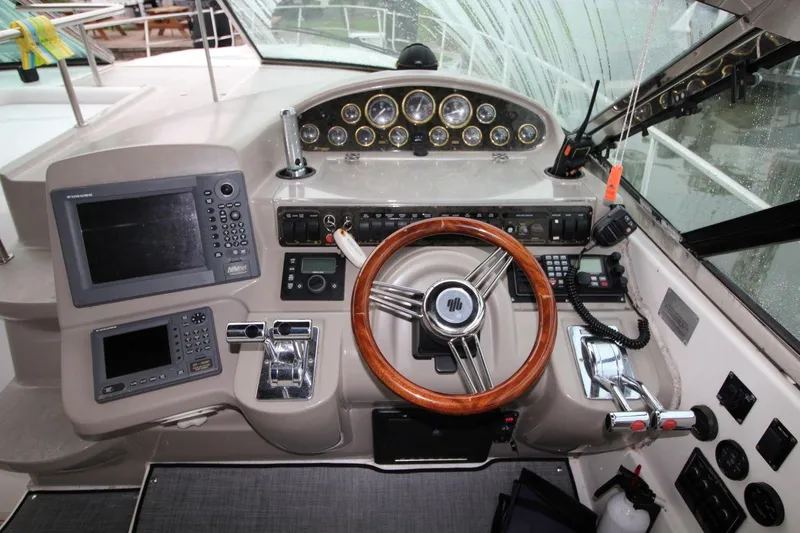Slide: The Image of 2002 Cruisers Yachts 4270 Express helm with wood steering wheel and navigation equipment. - 18