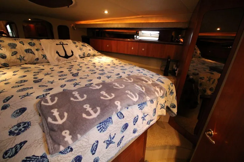 Slide: The Image of Luxurious 2002 Cruisers Yachts 4270 Express cabin with nautical-themed bedding and cozy lighting. - 25
