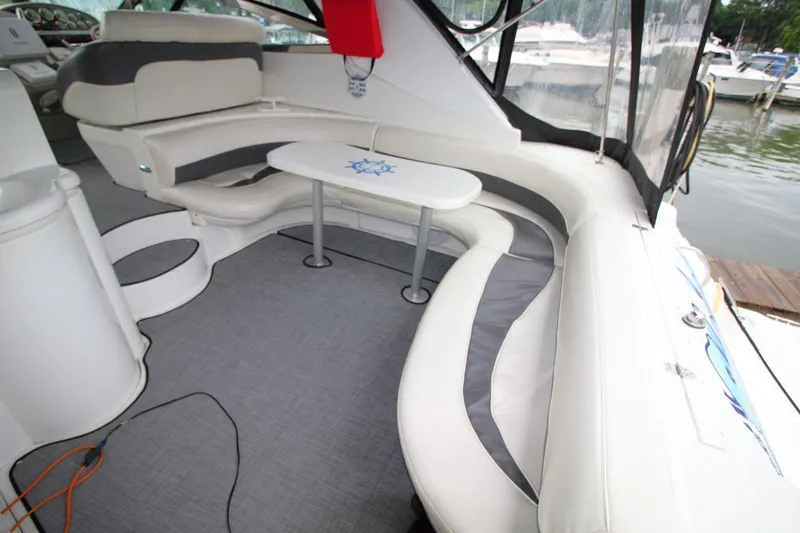 Slide: The Image of 2002 Cruisers Yachts 4270 Express interior with curved seating and table, dockside view. - 15