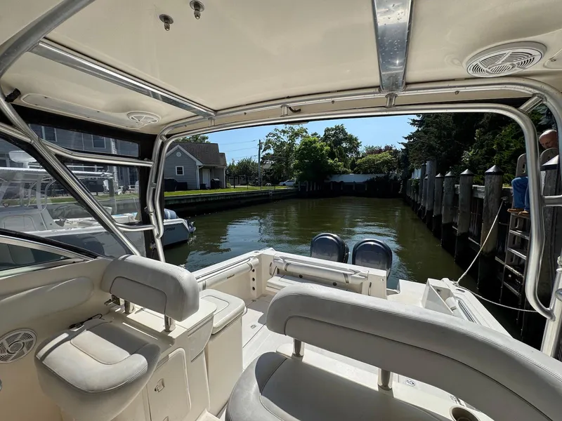 Slide: The Image of 2005 Wellcraft 290 Coastal boat interior with seating, docked in a calm canal. - 17
