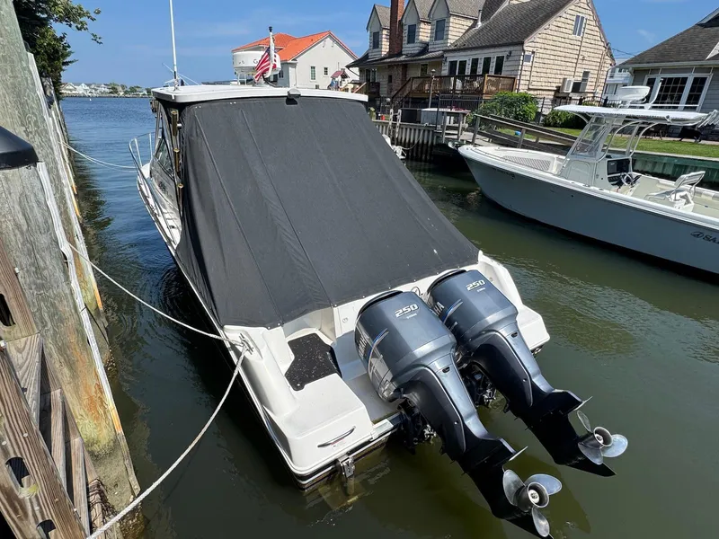 Slide: The Image of 2005 Wellcraft 290 Coastal boat docked with twin 250 horsepower engines, covered in black tarp. - 2